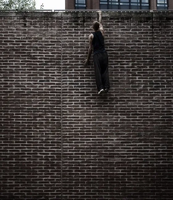 parkour runner dangles from wall