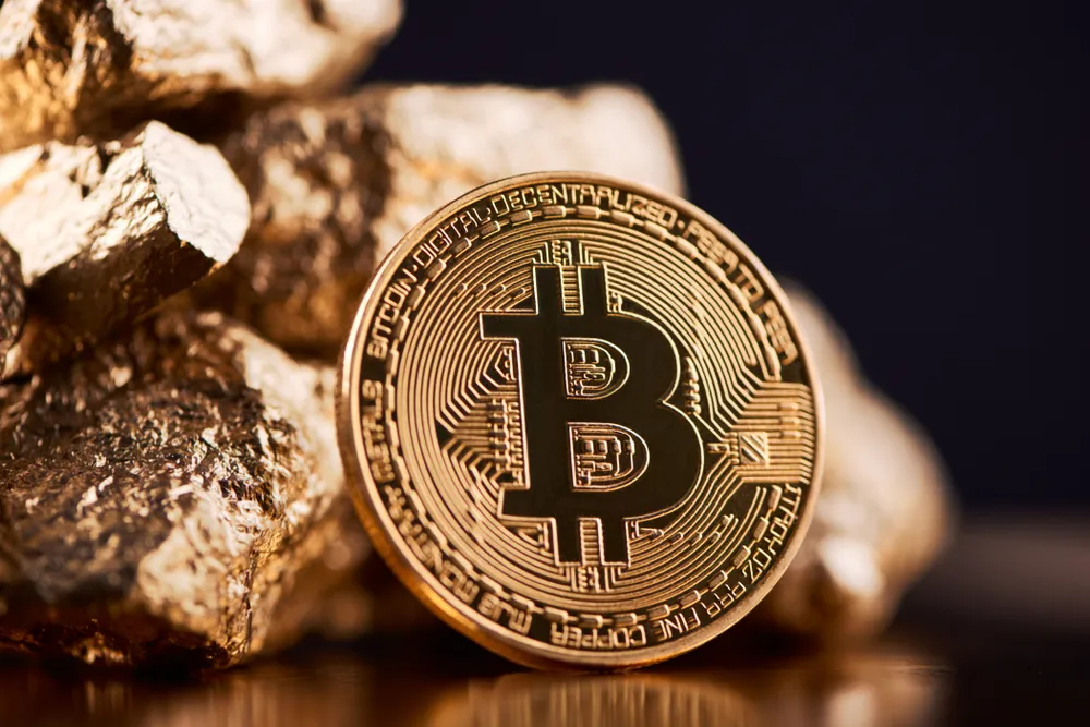 An image of a bitcoin coin next to some gold