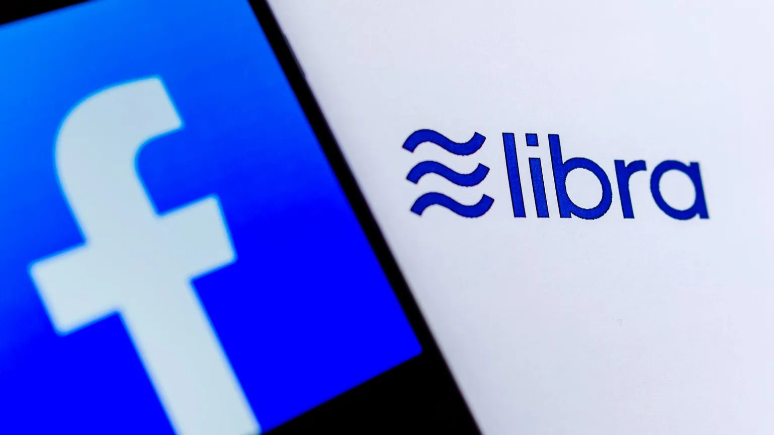 Photo of Facebook logo on the smartphone screen and the brochure with Libra logo