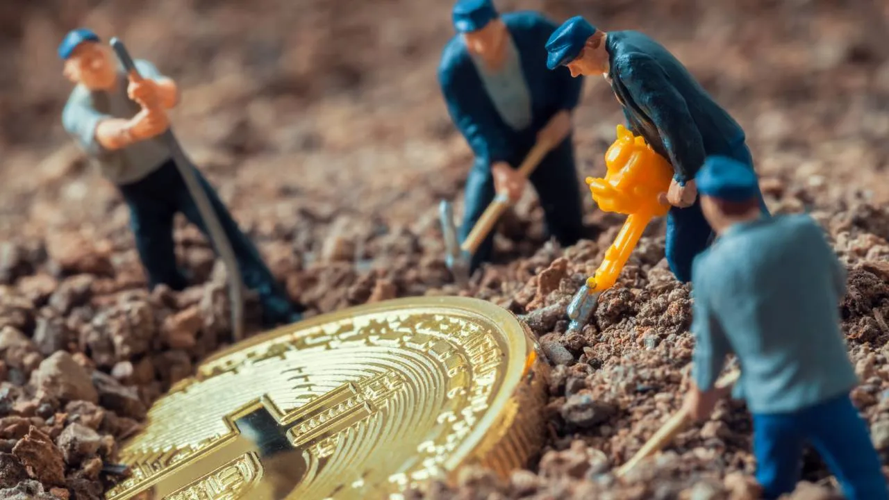 macro image of toy figures mining a gold Bitcoin
