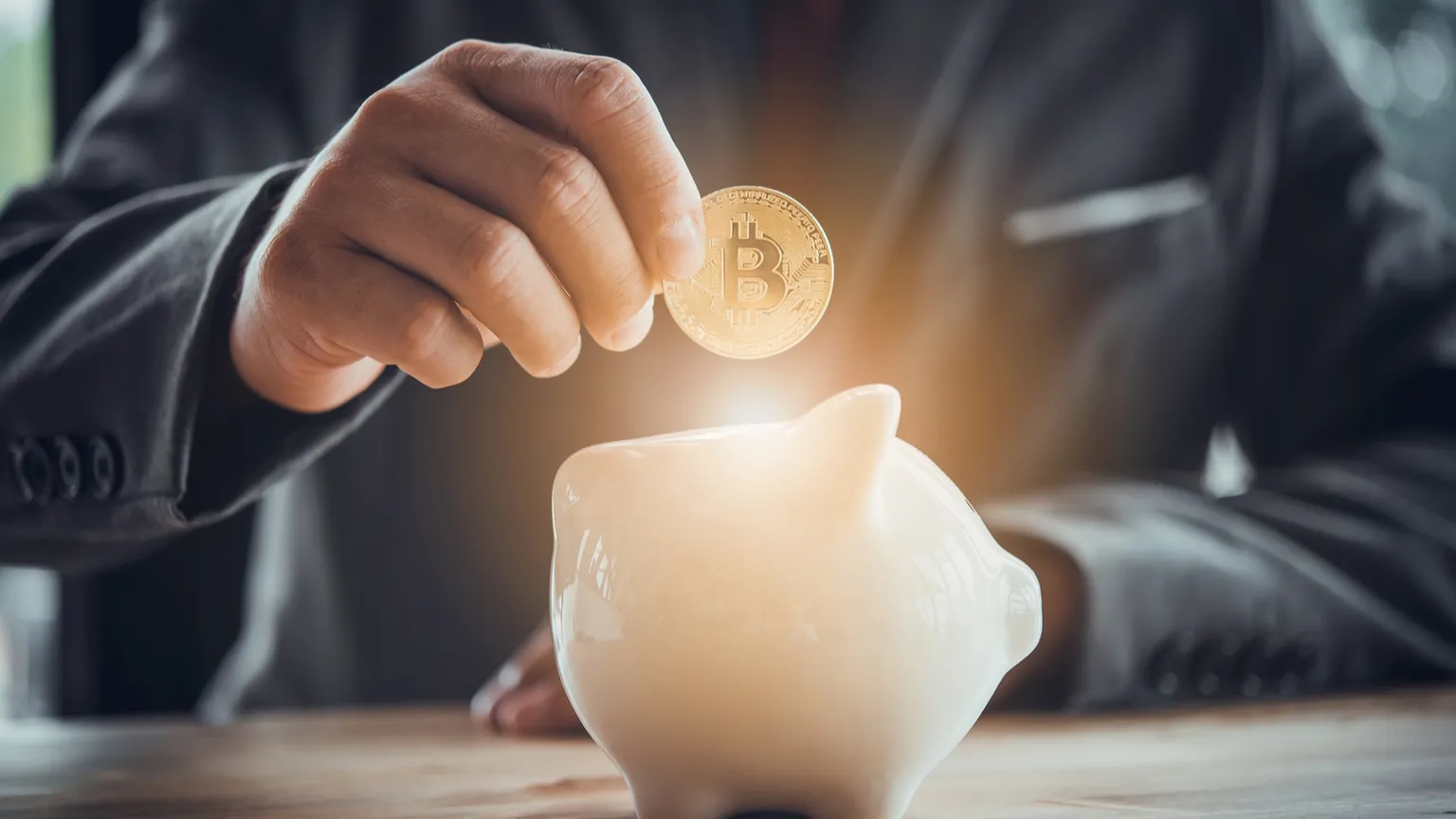 Businessman puts Bitcoin into piggy bank