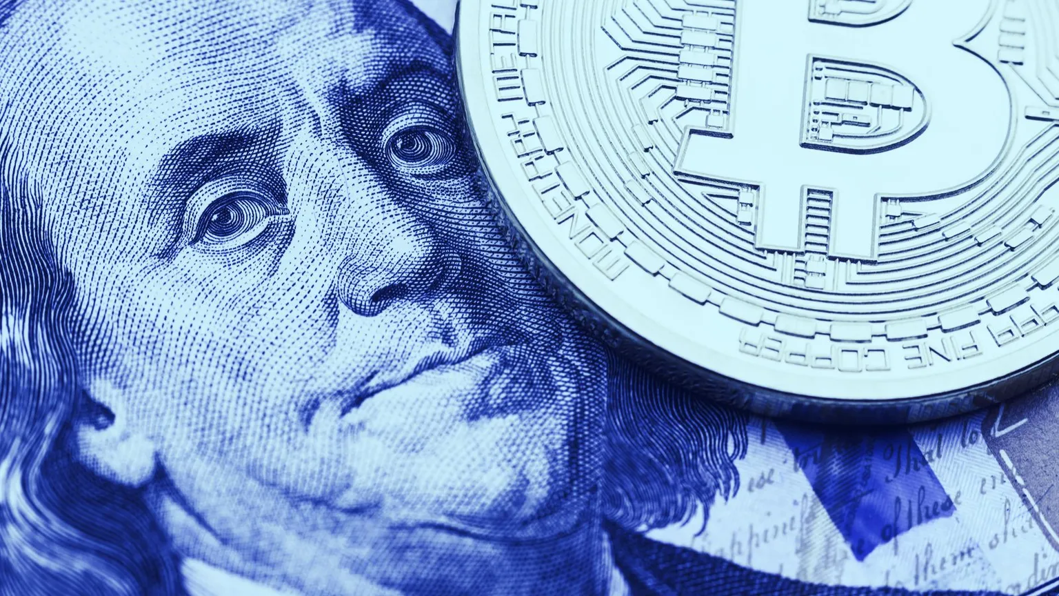 A Bitcoin on a 100 dollar bill. (Image: Shutterstock)