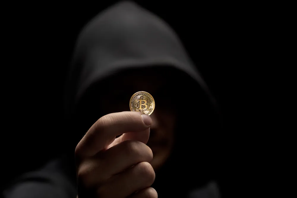 A hooded character holding Bitcoin