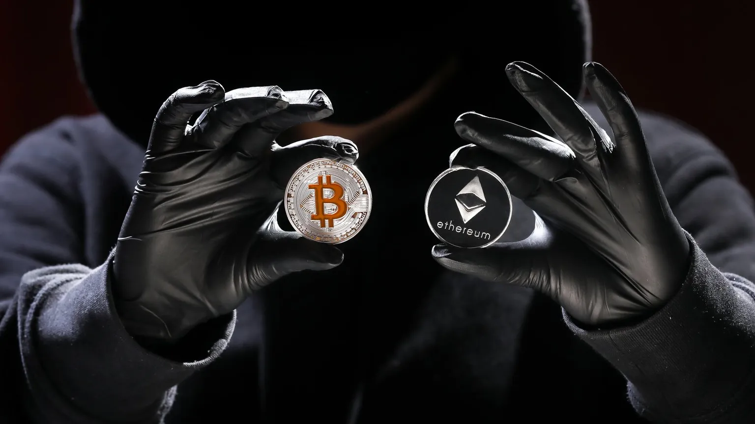 A hacker holding up Bitcoin and Ethereum coins. Image: Shutterstock