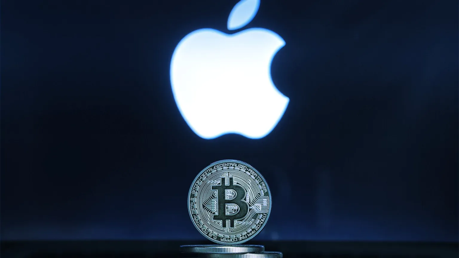 Slovenia / Ljublljana - 02 24 2019: Bitcoin on a stack of coins with Apple logo on a laptop screen.