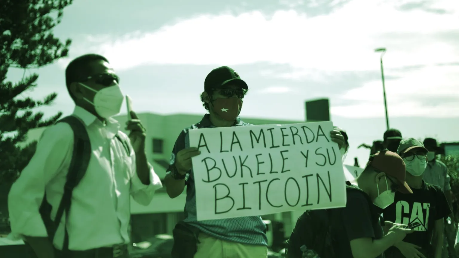 A man holding a sign roughly translated as "to hell with Bukele and his Bitcoin." Image: Shutterstock