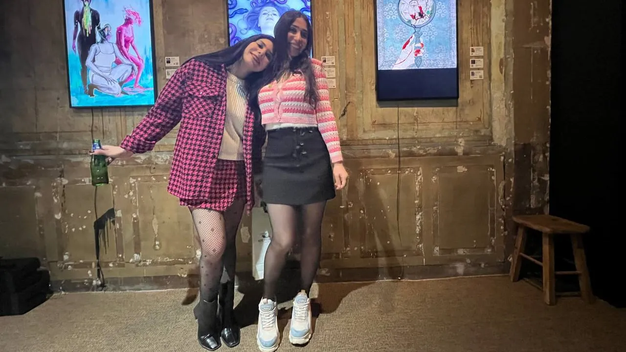 Two woman standing in front of digital art.