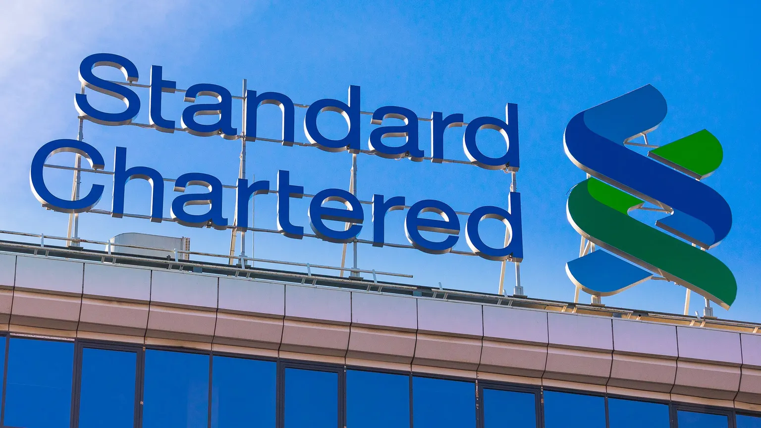 Standard Chartered company logo atop a building in Warsaw. Image: Konektus Photo / Shutterstock.com