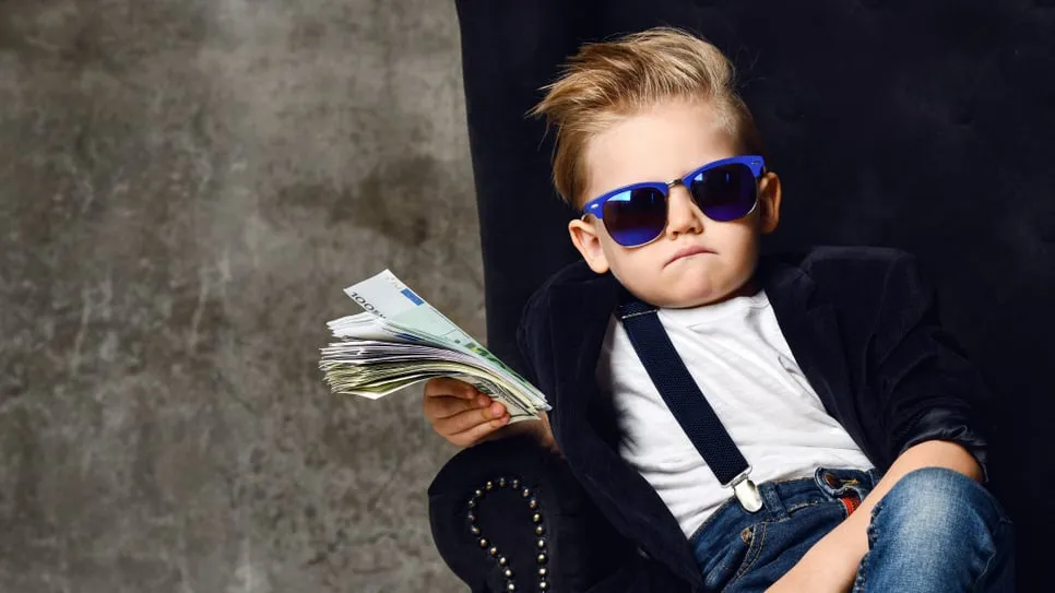A kid holding a wad of cash. Image: Shutterstock.