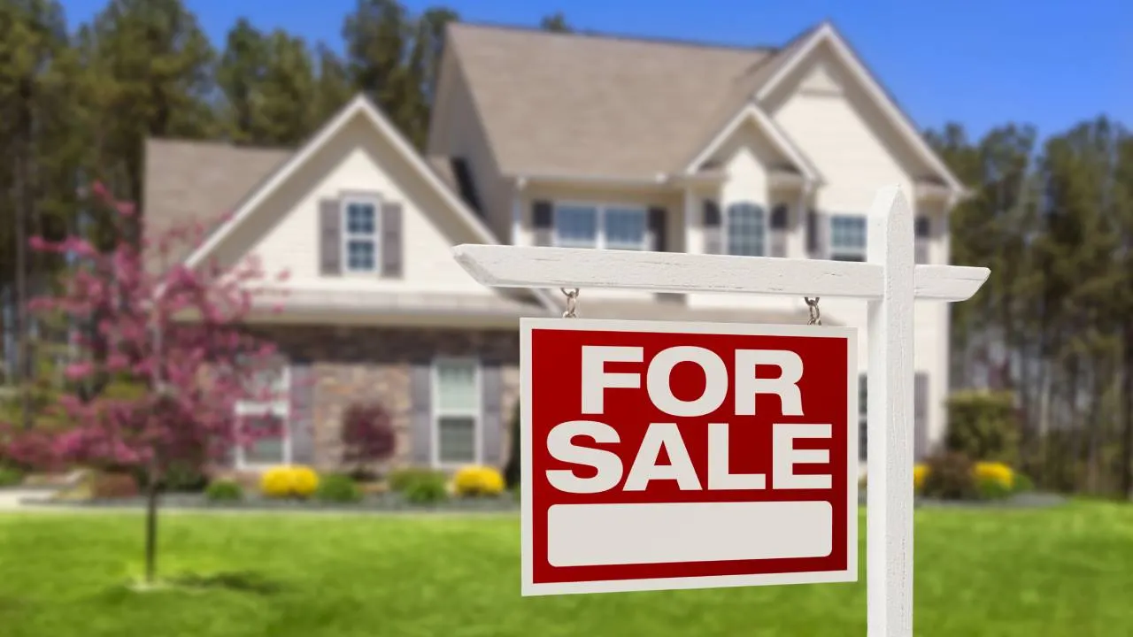 House with For Sale sign in foreground