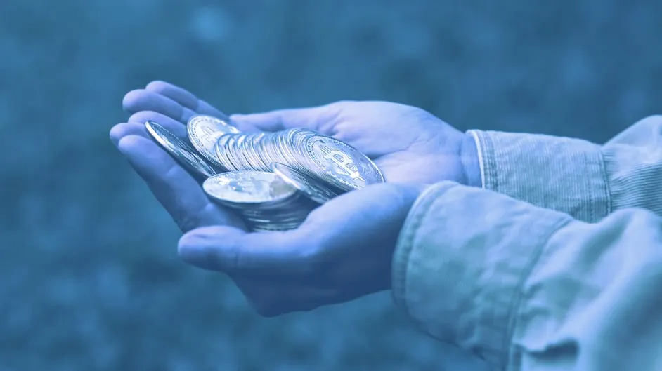 Someone holding a stash of coins representing Bitcoin. Image: Shutterstock.