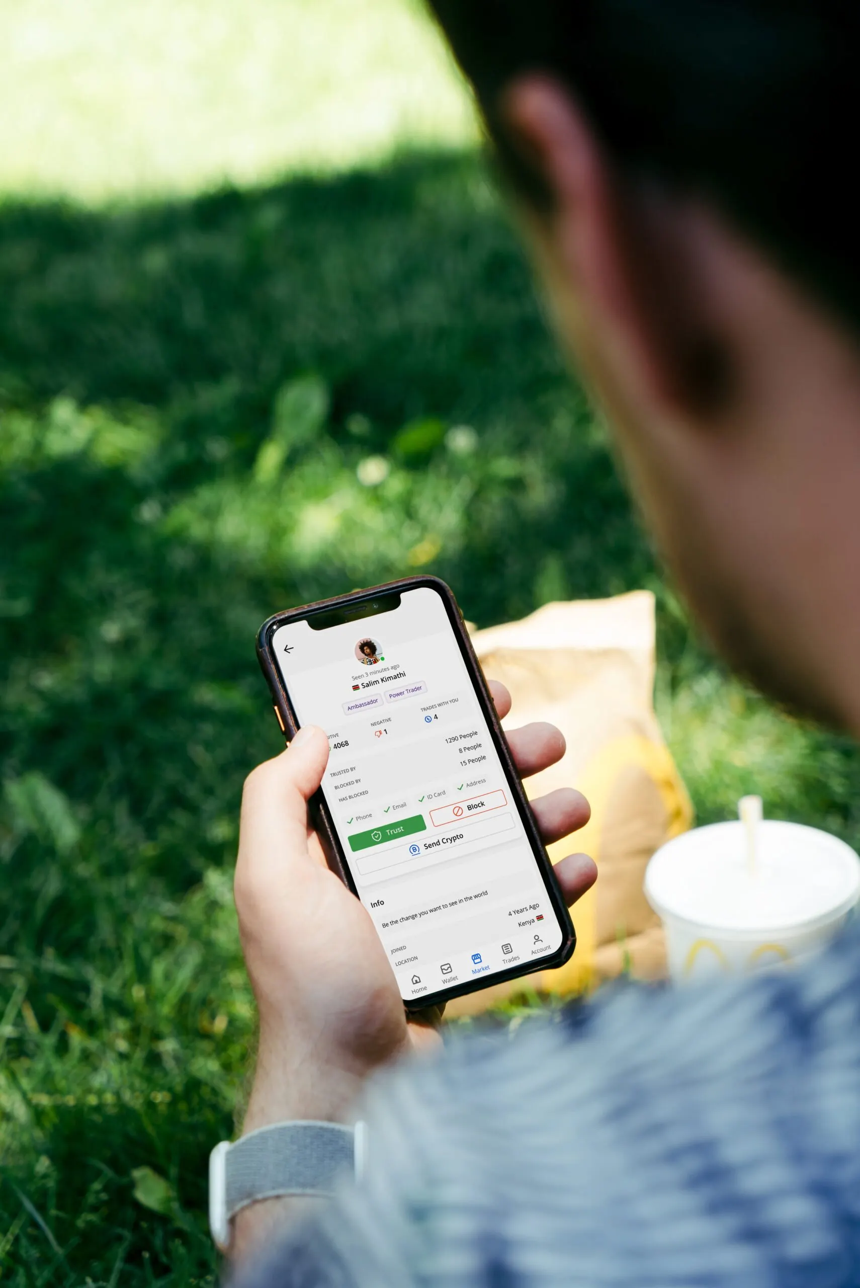 Person looking at a smartphone screen while sitting in the grass. 