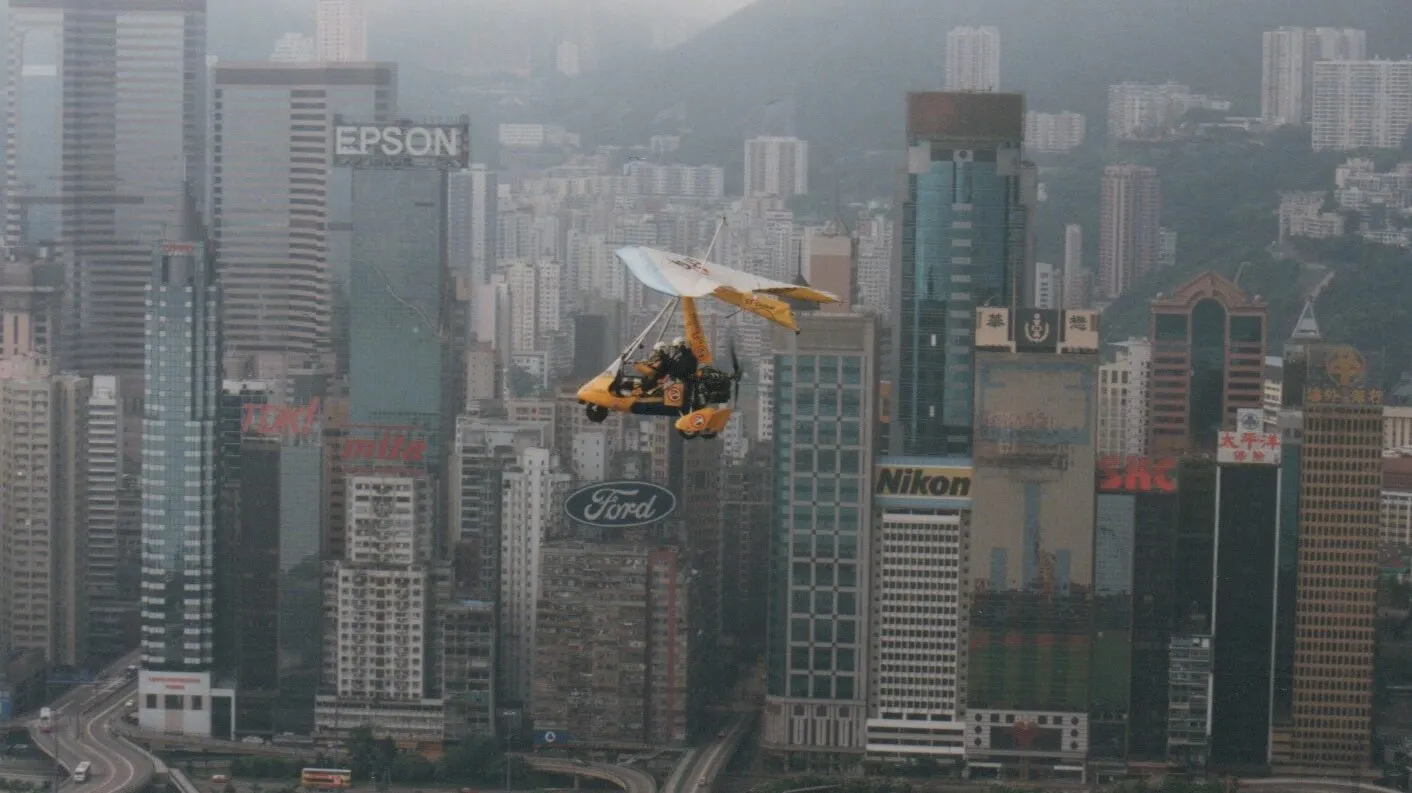 Microlight flying through cityscape