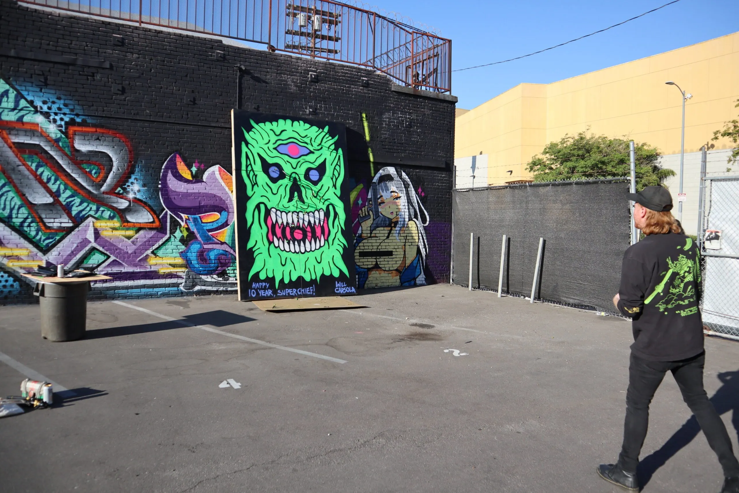 Ed Zipco in a parking lot throwing a knife at a painting.