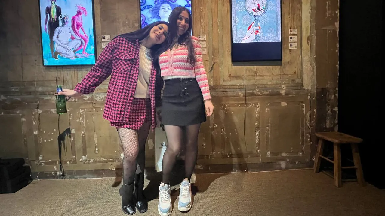 Two woman standing in front of digital art.