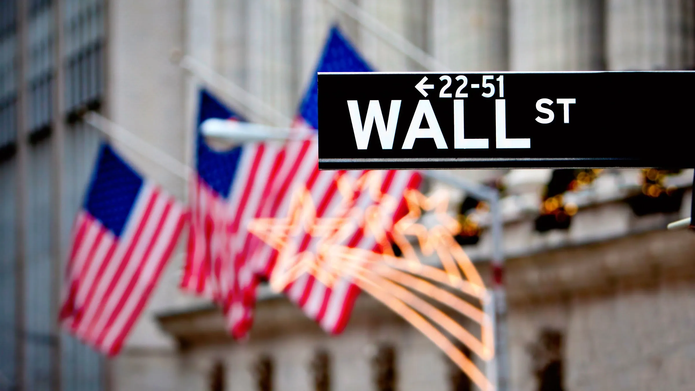 Wall street sign in New York with the New York Stock Exchange background. Image: Stuart Monk/Shutterstock