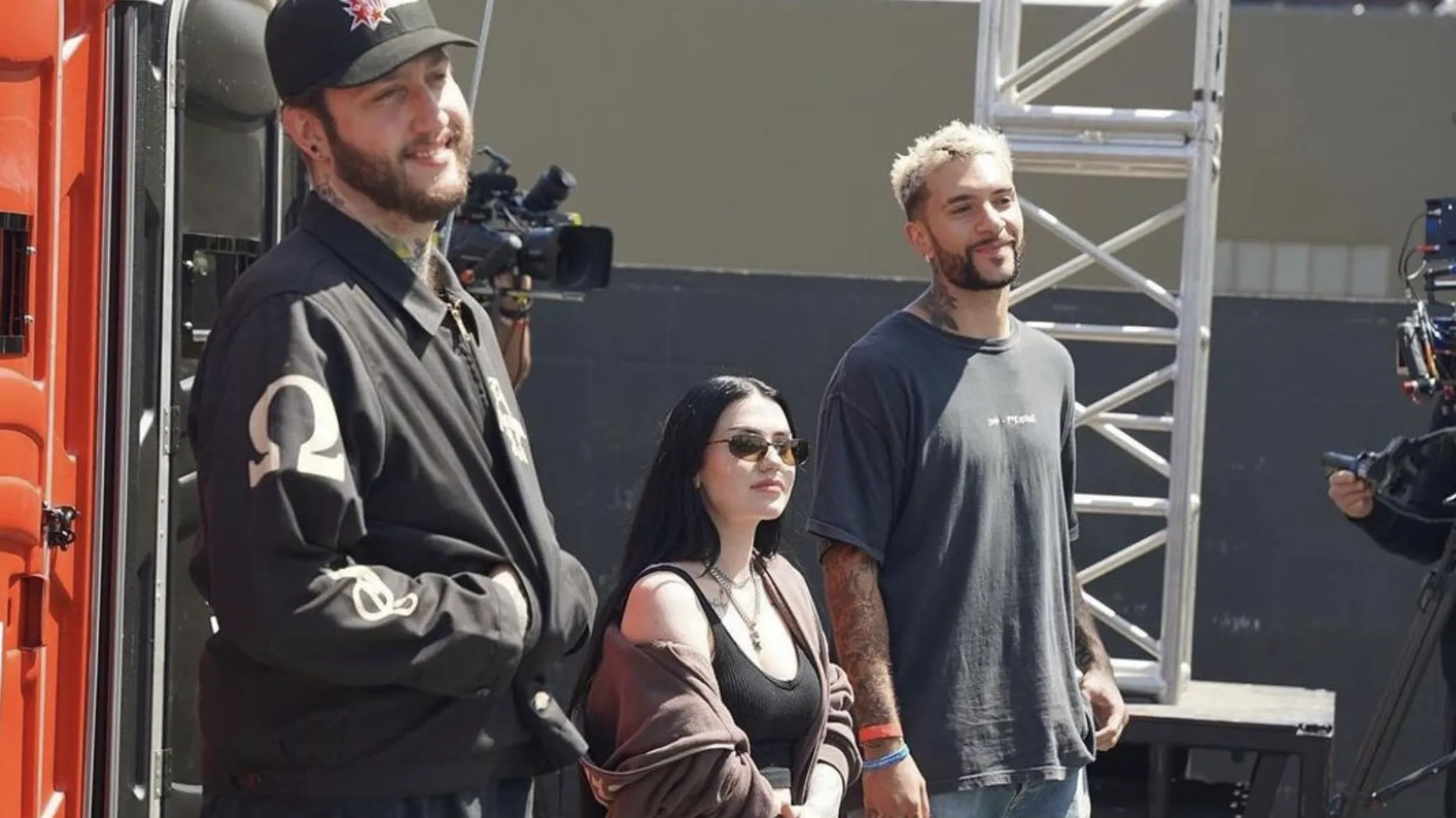 Photograph of Banks, Kalei, and Temperr. They're backstage on a film set, wearing all-black.