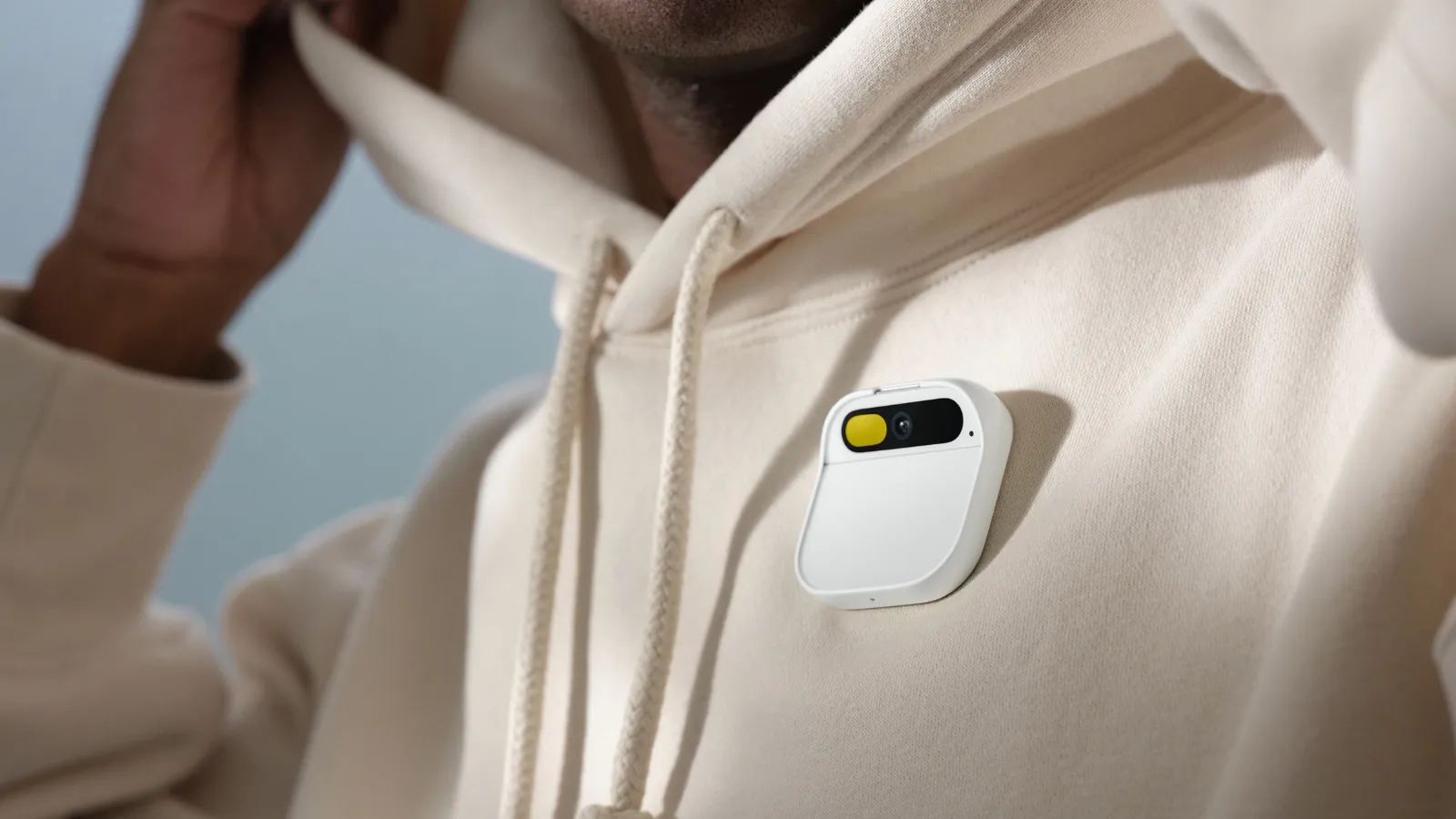 Man wearing a hoodie with a Humane AI Pin.