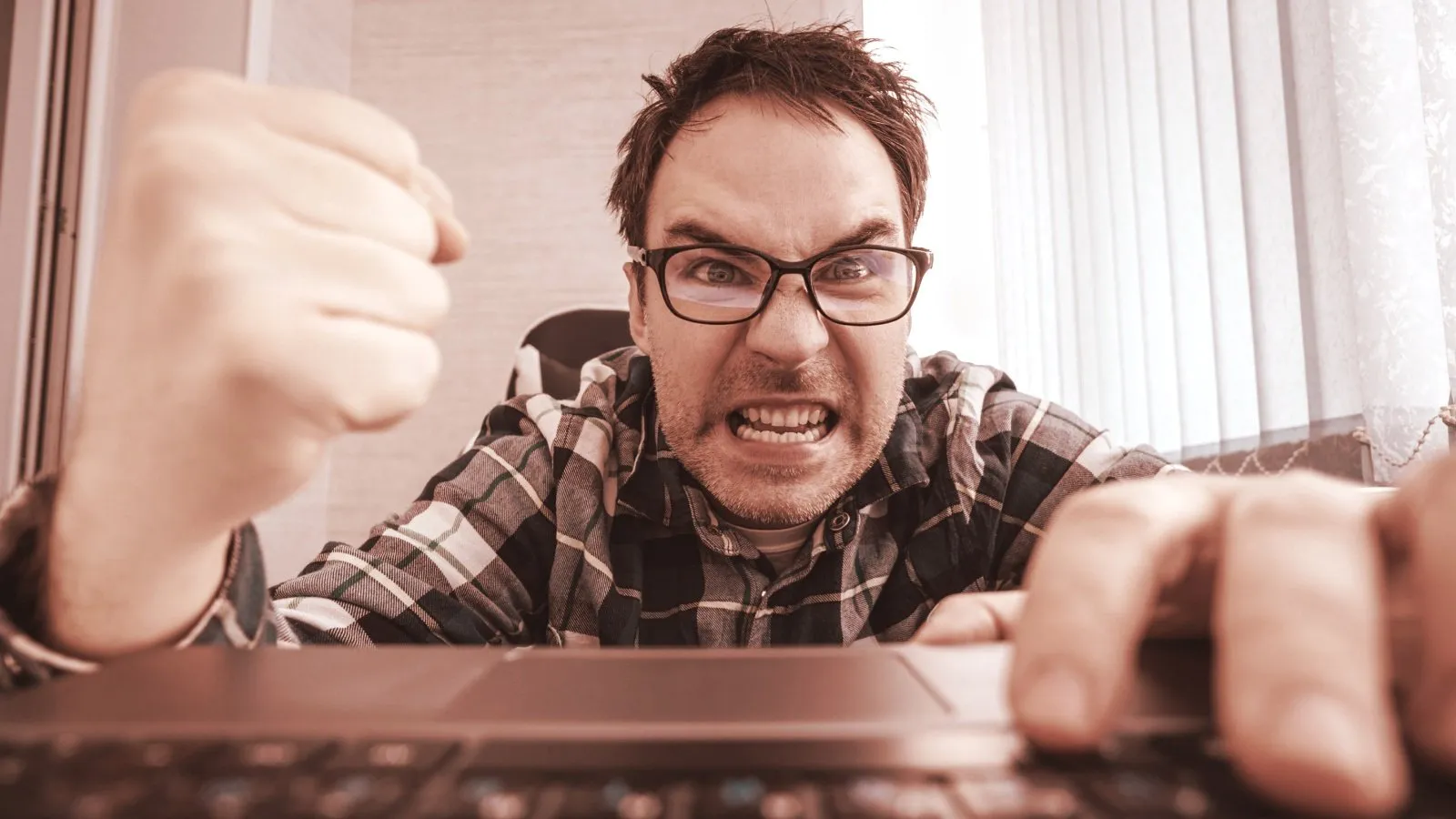 Angry man shaking fist at his computer. Image: Shutterstock.